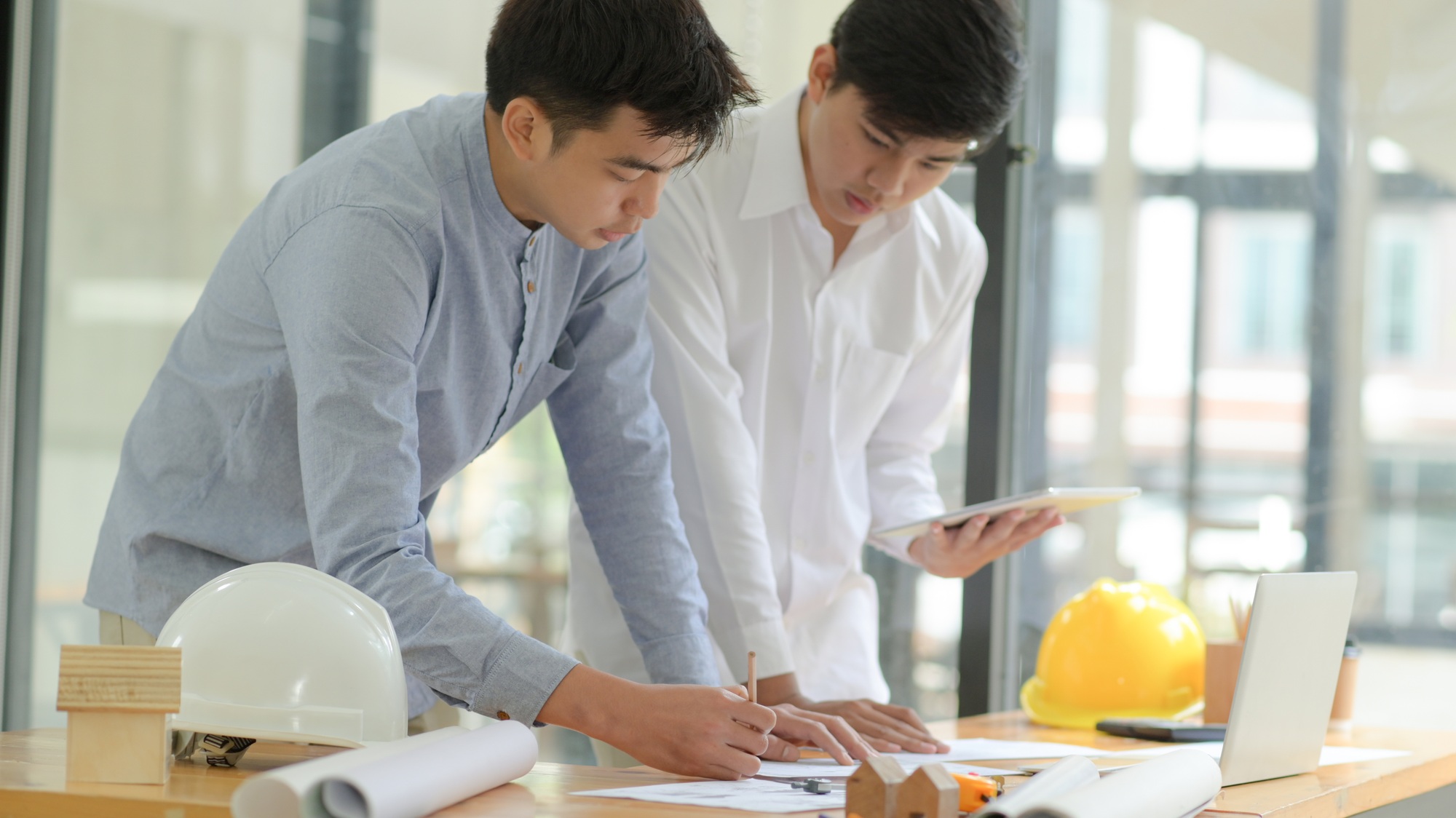 Architects and engineers inspect plans and consult for design and construction planning.